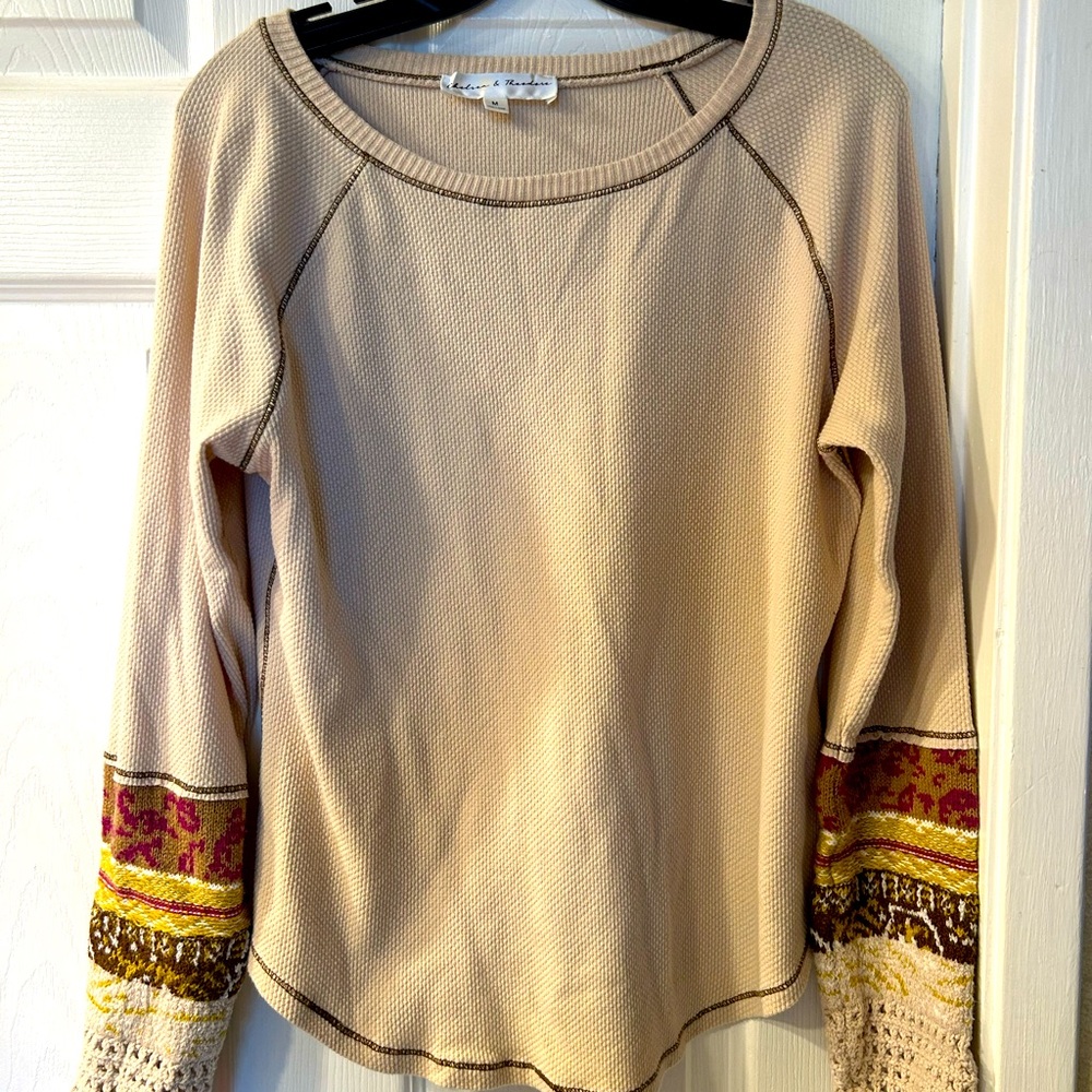 Crocheted sleeve accents. Looks great with a vest. Flattering rounded bottom.